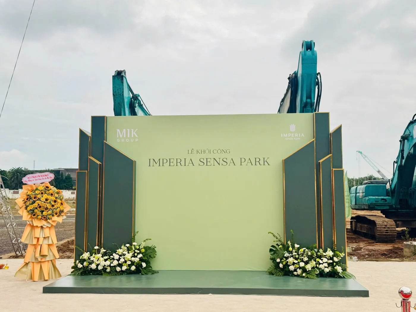 Máy đào tập kết phía sau backdrop lễ khởi công Imperia Sensa Park